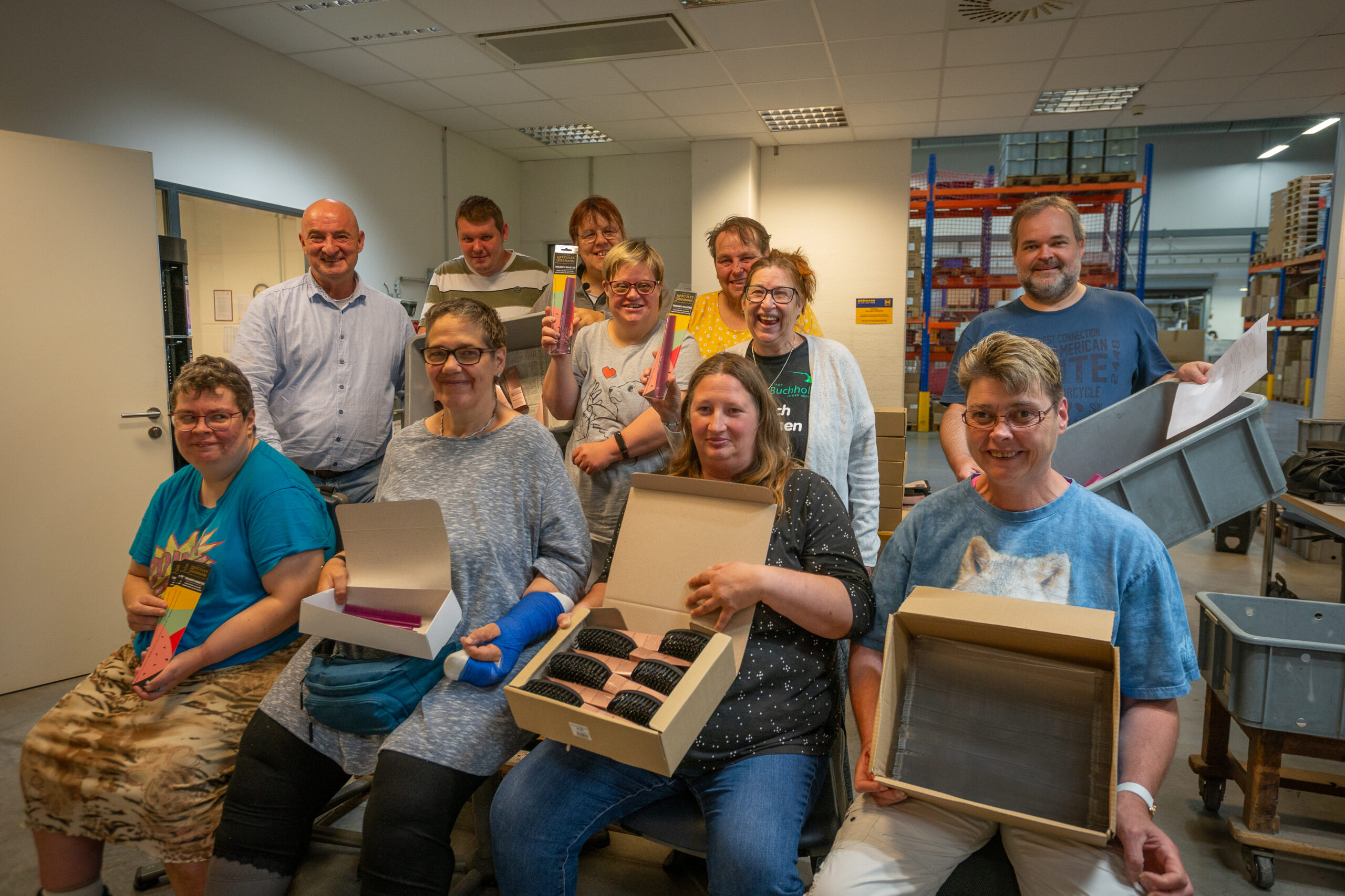 Gruppenfoto der gut gelaunten Mitarbeitenden, die Produkte der Firma zeigen. Foto: Berit Neß