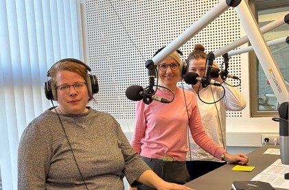 Beraterinnen sind bei Radio ZuSa zu Gast, stehen vor Mikrofonen und tragen Kopfhörer